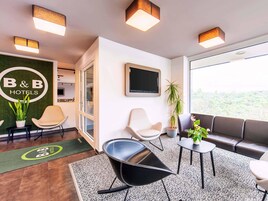 Un moderno vestíbulo de hotel con una pared verde, una recepción y zonas de estar.