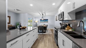 A modern kitchen with a central island, stainless steel appliances, and a dining area with a view. - Luxury Living & Heated Pool Near Anna Maria Island (Bradenton)