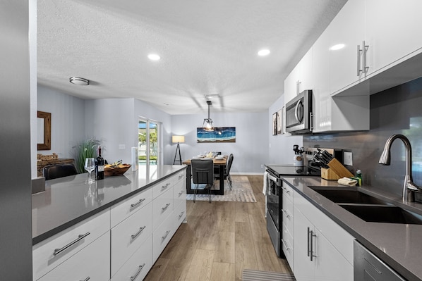 A modern kitchen with a central island, stainless steel appliances, and a dining area with a view.