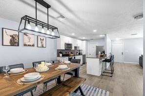 A modern kitchen with a wooden dining table, white cabinets, and a built-in island.