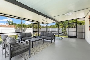 A covered outdoor seating area with a sofa, chairs, and a table.