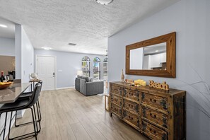 Une cuisine moderne avec des meubles en bois, un coin repas avec une table et des chaises, et un salon avec un canapé.