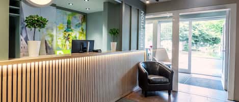 Una recepción con un cartel de B&B Hotels, una computadora y una planta en maceta.