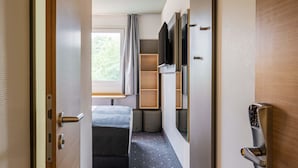 Una habitación moderna y compacta, con cama, televisión y espacio de almacenamiento integrado.