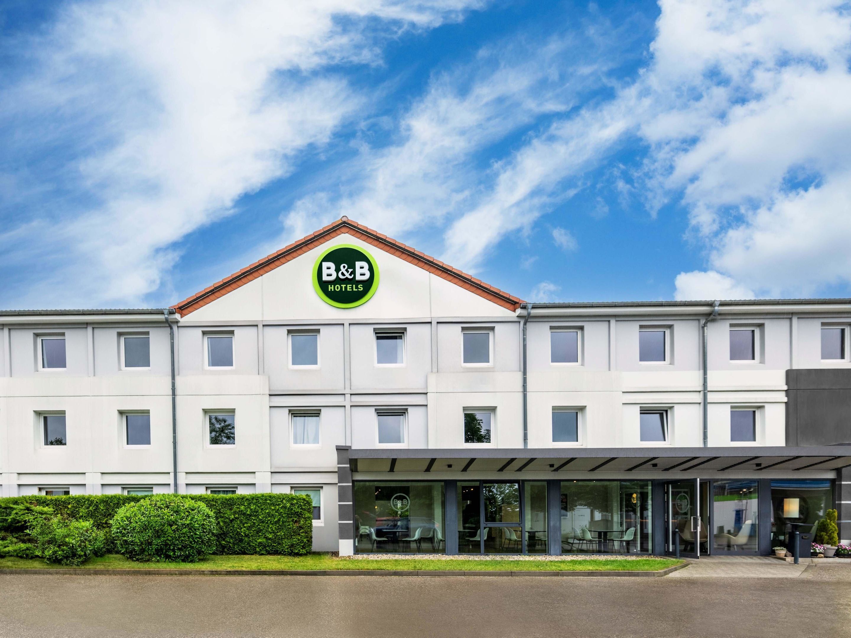 A B&B hotel with a modern facade, large windows, and a covered entrance.