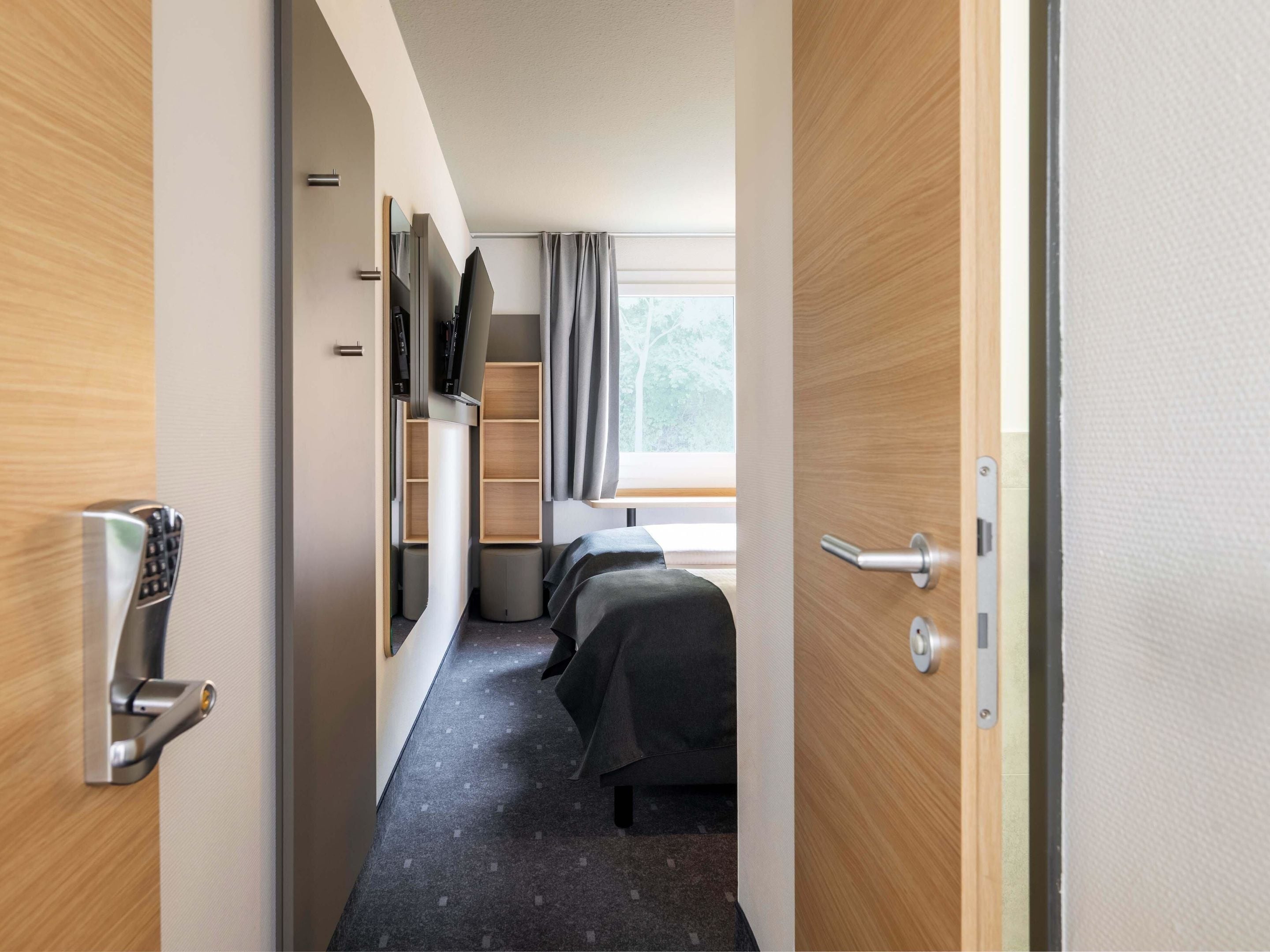 Una habitación de hotel con cama, televisión, escritorio y ventana con cortinas.