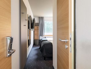 Een hotelkamer met een bed, een televisie, een bureau en een raam met gordijnen.