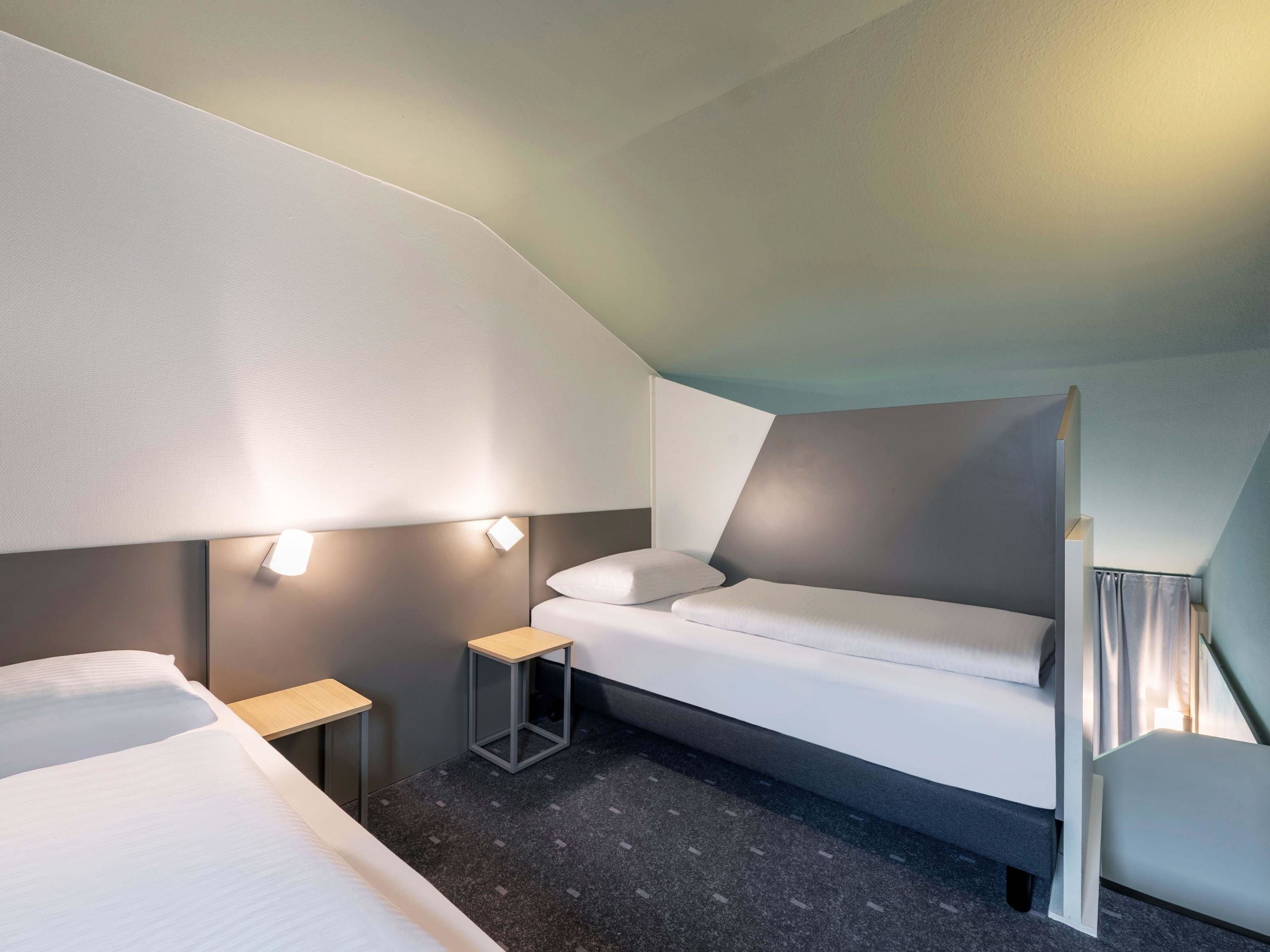 Ein modernes Hotelzimmer mit einem Etagenbett, einem kleinen Nachttisch und einer Wandleuchte.