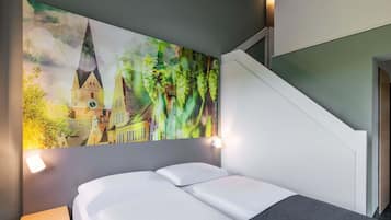 A hotel room with a bed, a small bedside table, and a large painting of a town scene on the wall.