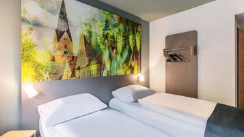 A hotel room with a bed, a nightstand, a wall-mounted coat rack, and a large cityscape painting.