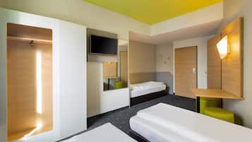 Ein Hotelzimmer mit zwei Einzelbetten, einem an der Wand befestigten Fernseher und einem Spiegel über dem Bett.