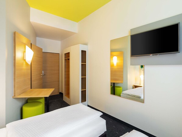 A hotel room with a bed, a TV mounted on the wall, a mirror, and a wardrobe. - B&B Hotel Mülheim an der Ruhr (Muelheim an der Ruhr)