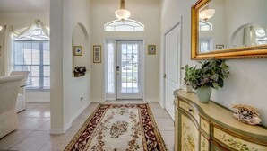 Un couloir avec un tapis à motifs floraux, un grand miroir et un meuble décoratif.