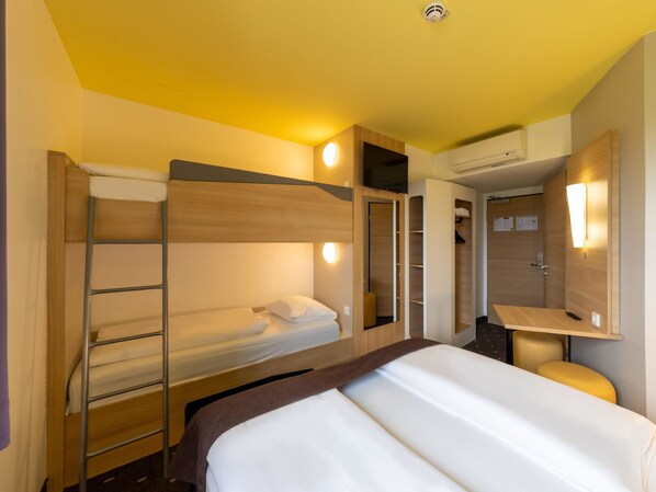 Une chambre d’hôtel avec des lits superposés, une table de chevet, un miroir et une armoire.