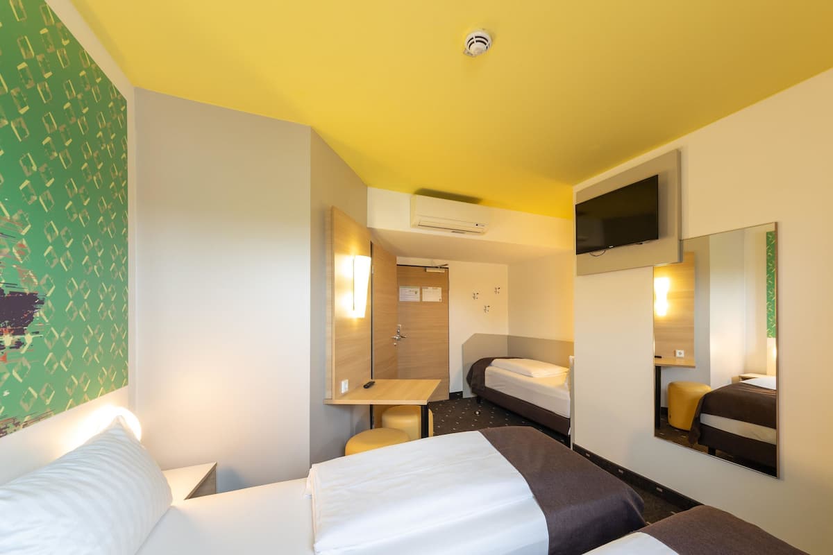 Habitació d'hotel amb dos llits, una taula de treball, un mirall i una televisió.