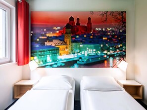 A hotel room with two beds, a large pixelated cityscape painting on the wall, and a window with red curtains. - B&B Hotel Passau-West (Passau)