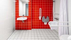 A modern bathroom with a red tiled wall, a white sink, a mirror, a shower, and a toilet. - B&B Hotel Passau-West (Passau)