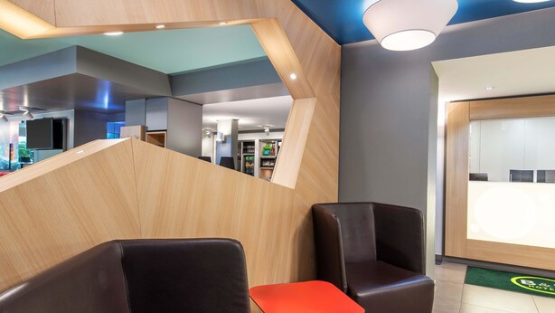 A modern hotel lobby with leather seating, a reception desk, and a blue ceiling. - B&B Hotel Passau-West (Passau)
