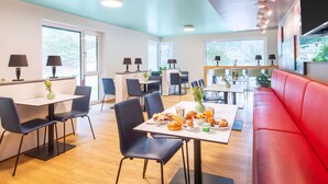 A modern dining area with tables, chairs, and a red sofa. - B&B Hotel Passau-West (Passau)