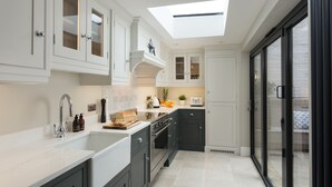 A modern kitchen with a skylight, white cabinets, and a black oven. - 4 St Martins Lane. Luxurious Central York Town House. Newly refurbished (York)