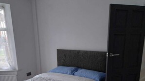 A bedroom with a bed, a window, and a door. - Remarkable 3-bed House in Hounslow (Hounslow)