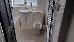 A small, compact bathroom with a toilet, sink, and storage cabinets. - Remarkable 3-bed House in Hounslow (Hounslow)