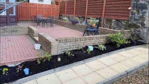 A patio area with brick flooring, a wooden fence, and outdoor furniture. - 1 Bed House - Central, Free Parking, Wifi (Stirling)