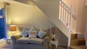 A living room with a sofa, two lamps, a small table, and a staircase. - 1 Bed House - Central, Free Parking, Wifi (Stirling)