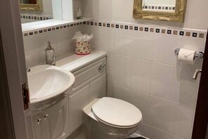 A bathroom with a white sink, toilet, and a mirror above the sink. - 1 Bed House - Central, Free Parking, Wifi (Stirling)