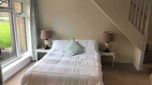 A bedroom with a large bed, two bedside tables with lamps, a window with curtains, and a view of a green landscape. - 1 Bed House - Central, Free Parking, Wifi (Stirling)