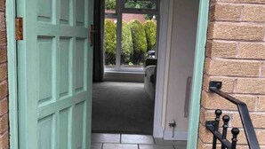 A doorway leading to a tiled hallway with a green door and a black metal railing. - 1 Bed House - Central, Free Parking, Wifi (Stirling)