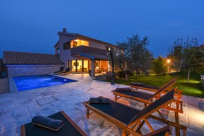 A modern house with a swimming pool, outdoor seating, and a well-lit patio area. - Villa Trabakul (Razanac)