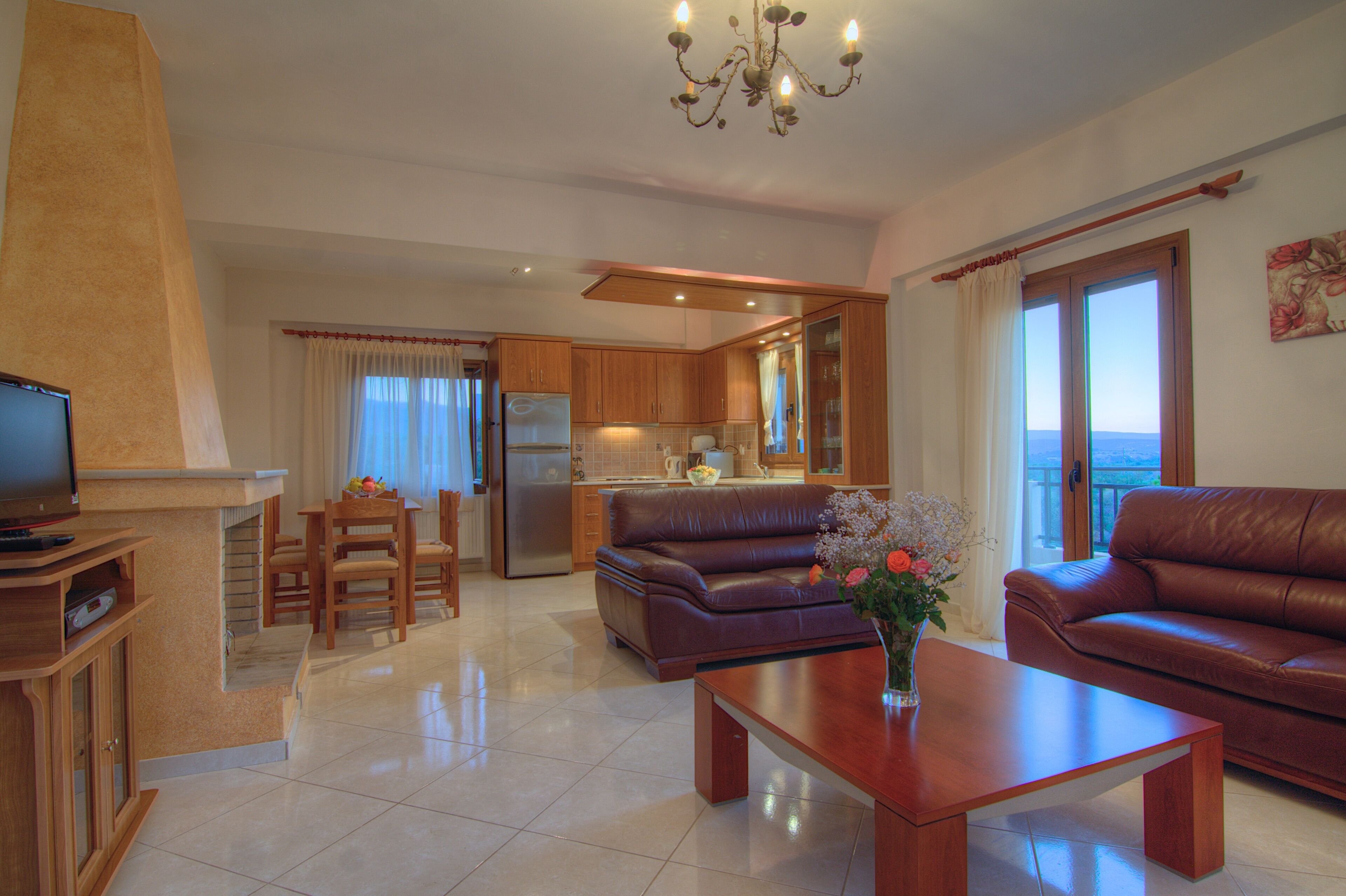 A modern living room with a television, a sofa, a coffee table, and a dining area with chairs and a table.