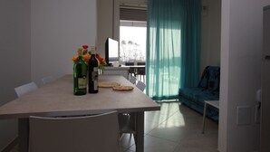 A dining area with a table, chairs, a bottle of wine, and a pizza. - Wonderful attic flat with sea view (Rosolina Mare)