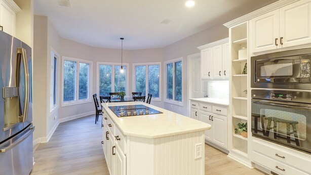Una cocina moderna con una isla central, muebles blancos y electrodomésticos integrados.