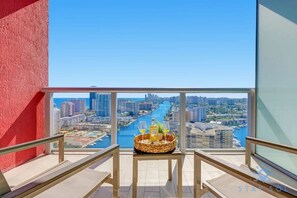A balcony with a city view, a wicker basket with drinks, and a clear sky.