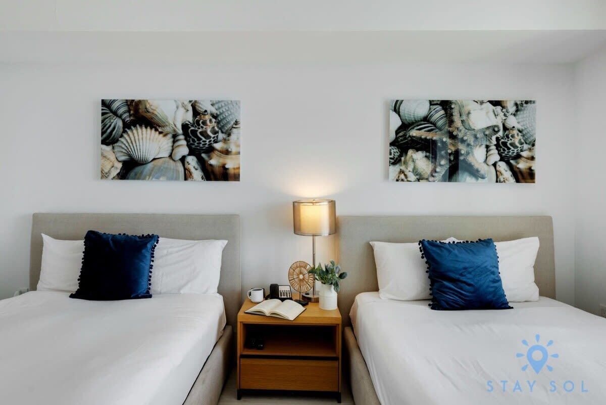 Ein Hotelzimmer mit zwei Betten, einem Nachttisch mit Lampe und einem Bild an der Wand.
