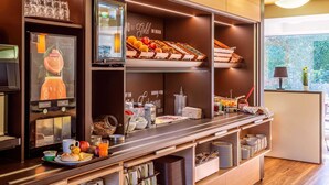 Un comptoir-repas proposant une variété d’aliments, une machine à café et une fenêtre donnant sur un paysage verdoyant.