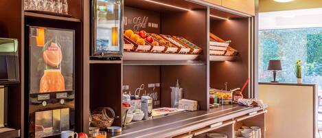A breakfast bar with a variety of food items, a coffee machine, and a window with a view of greenery.
