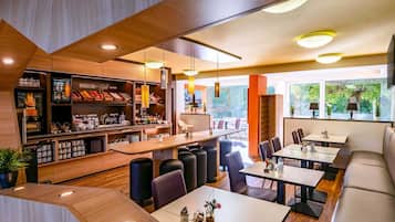 Ein modernes Restaurant mit Barbereich, Sitzgelegenheiten und großen Fenstern mit Blick ins Freie.