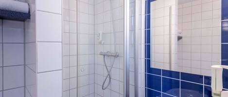 Un baño con ducha, lavamanos y espejo.