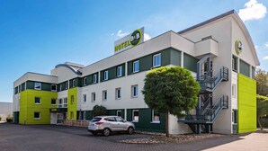 Un hôtel-restaurant de type « bed and breakfast » au design moderne, doté d’un parking et où une voiture est garée devant.