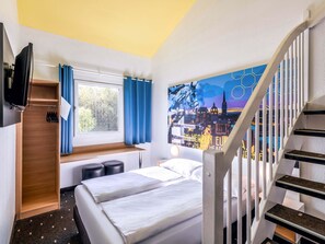 A hotel room with a bed, a desk, a window with curtains, a painting on the wall, and a staircase. - B&B Hotel Aachen-Würselen (Wuerselen)