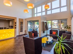 A modern lobby with a reception desk, seating area, and large windows. - B&B Hotel Aachen-Würselen (Wuerselen)