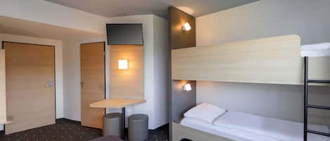 A hotel room with a bunk bed, a desk with a chair, and a small table. There are two doors, one of which is open.