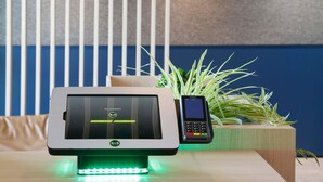 A B&B hotel room with a modern payment terminal, a small plant, and a window with vertical blinds. - B&B Hotel Berlin-Airport (Schoenefeld)