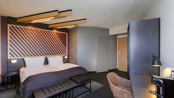 Una habitación de hotel moderna con cama, mesitas de noche, escritorio, silla y cafetera.