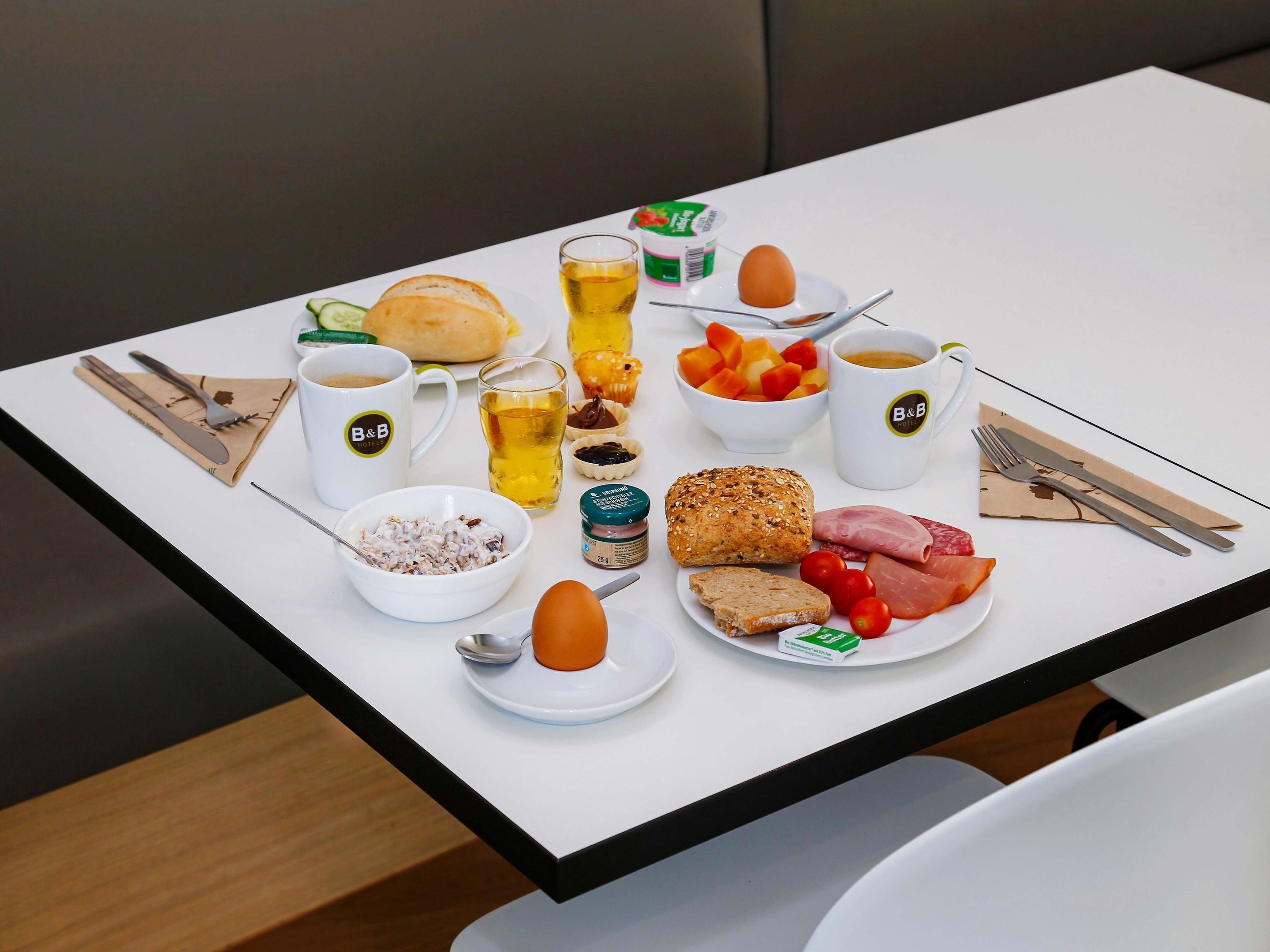 A breakfast table with various food items, including bread, eggs, and fruit.