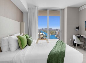 Relax in a spacious room with a large bed, desk, and city view.