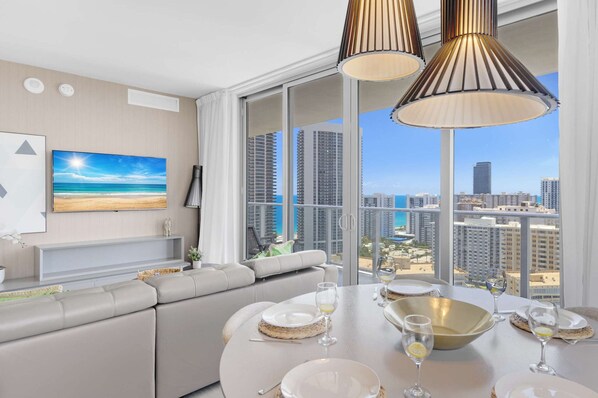Enjoy meals with a city and beach view from this stylish dining area, featuring a round table for four and pendant lights.